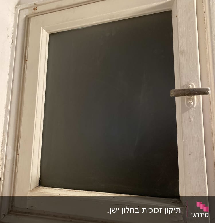 חלון עם זכוכית כהה במסגרת עץ לבנה